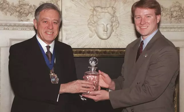 FILE - Charles "Chuck" Porter IV receives an award for his picture of a firefighter holding a baby in the aftermath of the Oklahoma bombing in London's Mansion House from the Lord Mayor of London Alderman John Chalstrey, right, on Jan. 26 1996, in London's Mansion House. (AP Photo/Dave Caulkin, File)