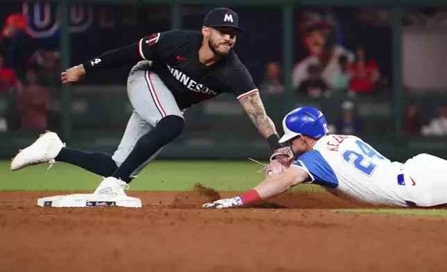Atlanta Braves' Jarred Kelenic (24) dives into second base against Minnesota Twins shortstop Carlos Correa, left, during the sixth inning of a baseball game Saturday, April 19, 2025, in Atlanta. After a review, Correa was ruled out on the play. (AP Photo/John David Mercer)
