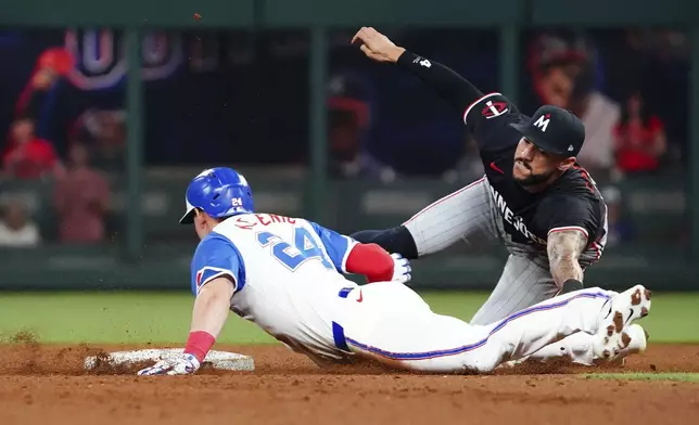 Atlanta Braves' Jarred Kelenic (24) dives into second base against Minnesota Twins shortstop Carlos Correa, right, during the sixth inning of a baseball game Saturday, April 19, 2025, in Atlanta. After a review, Correa was ruled out on the play. (AP Photo/John David Mercer)