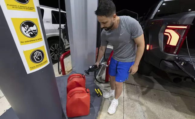 A local fills fuel containers at a gas station in San Juan, Puerto Rico, during an island-wide blackout, Wednesday, April 16, 2025. (AP Photo/Alejandro Granadillo)