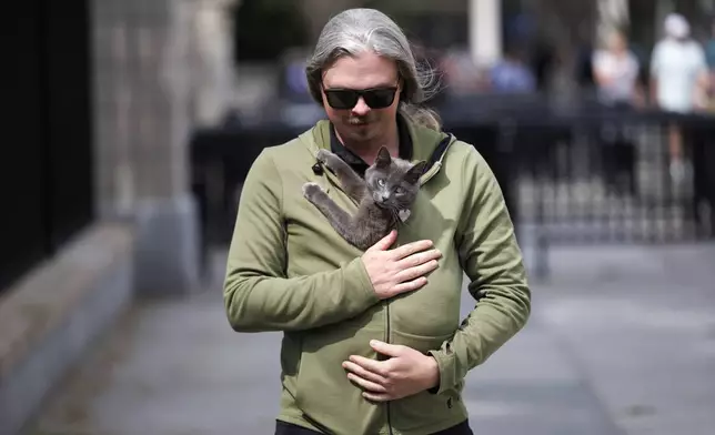 Alec Augustine carries his cat Sophie outside the White House after she was found wandering the White House grounds, Friday, April 18, 2025, in Washington. (AP Photo/Tom Brenner)