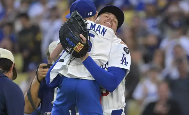 Los Angeles Dodgers first baseman Freddie Freeman hugs his 9-year-old son Charlie after he threw out the first pitch before a baseball game against the Chicago Cubs, Friday, April 11, 2025, in Los Angeles. (AP Photo/Jayne Kamin-Oncea)