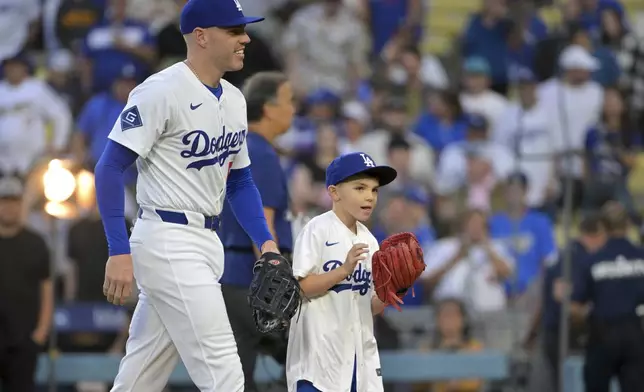 Los Angeles Dodgers first baseman Freddie Freeman walks with his 9-year-old son Charlie after he threw out the first pitch before a baseball game against the Chicago Cubs, Friday, April 11, 2025, in Los Angeles. (AP Photo/Jayne Kamin-Oncea)