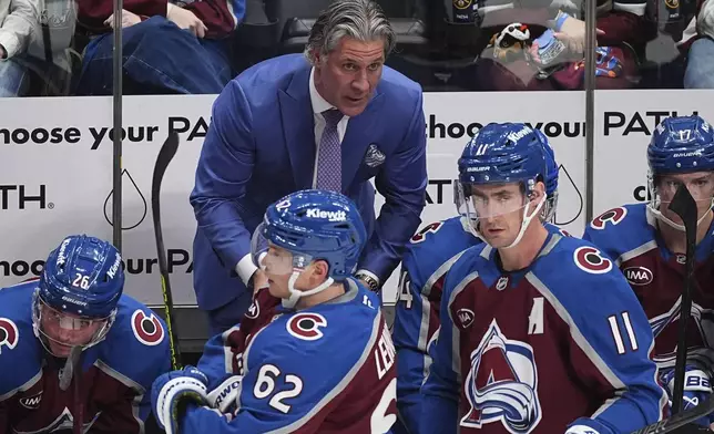 Colorado Avalanche head coach Jared Bednar, back, draws up a play for players during a time out in the third period of an NHL hockey game against the Vancouver Canucks Thursday, April 10, 2025, in Denver. (AP Photo/David Zalubowski)