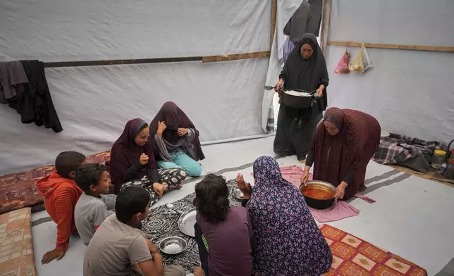 The Al-Najjar family prepares for a meal of peas with rice in their family tent in Muwasi, on the outskirts of Khan Younis in the southern Gaza Strip, Friday, April, 25, 2025(AP Photo/Abdel Kareem Hana)