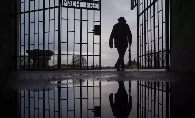 FILE - A man walks through the gate of the Sachsenhausen Nazi death camp with the phrase 'Arbeit macht frei' (work sets you free) at the International Holocaust Remembrance Day, in Oranienburg, about 30 kilometers, (18 miles) north of Berlin, Germany, Jan. 27, 2019. (AP Photo/Markus Schreiber, File)