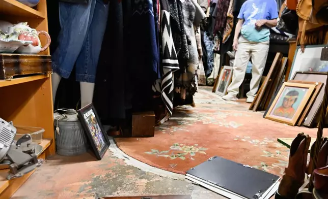 Tracy Turner, owner of the Wynola Junction, looks over pictures that fell from shelves when a earthquake hit Monday, April 14, 2025, in Julian, Calif., after an earthquake shook Southern California, sending boulders tumbling onto rural roadways outside San Diego and rattling items off shelves and walls. (AP Photo/Denis Poroy)