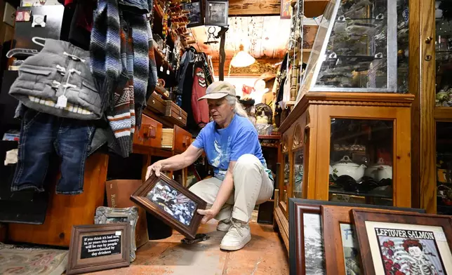 Tracy Turner, owner of the Wynola Junction, looks over pictures that fell from shelves when a earthquake hit Monday, April 14, 2025, in Julian, Calif. (AP Photo/Denis Poroy)