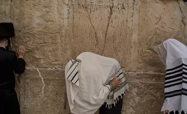 Covered in prayer shawls, Jewish men of the Cohanim Priestly caste participate in a blessing during the holiday of Passover, at the Western Wall, the holiest site where Jews can pray, in the Old City of Jerusalem, Tuesday, April 15, 2025. (AP Photo/Leo Correa)