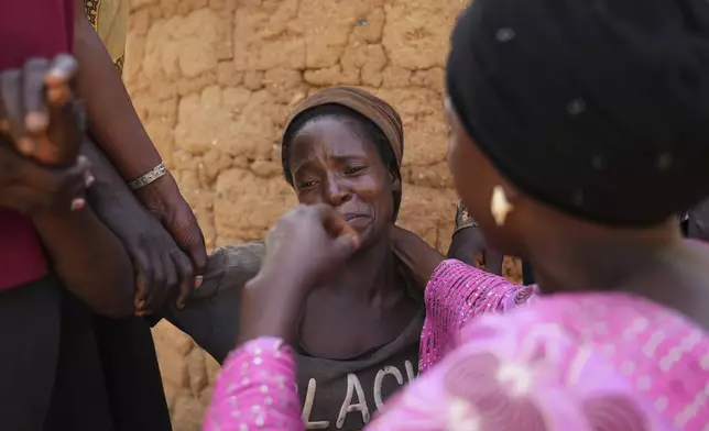 Women mourn the death of a family member following an attack by gunmen in the Zike farming community in north-central Nigeria, Tuesday, April 15, 2025. (AP Photo/Samson Omale)