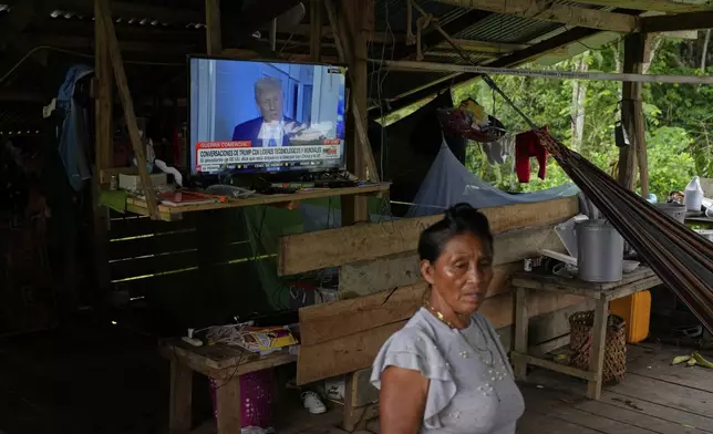 A woman stands at her home where she has the news on, showing U.S. President Donald Trump, in Villa Caleta, a community in Panama that used to benefit economically by being on the route migrants took after crossing the Darien Gap on their way north to the U.S., Monday, April 7, 2025. (AP Photo/Matias Delacroix)