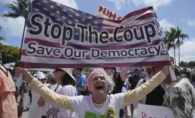 Protesters carry signs and chant slogans against the policies of President Donald Trump and Elon Musk Saturday, April 5, 2025, in Miami. (AP Photo/Marta Lavandier)