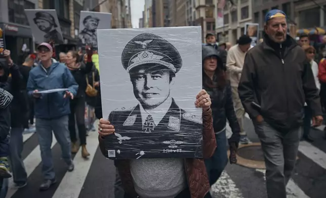A demonstrator carries a photo depicting Elon Musk in a uniform as they take to the streets and march during a protest against President Donald Trump on Saturday, April 5, 2025, in New York. (AP Photo/Andres Kudacki)