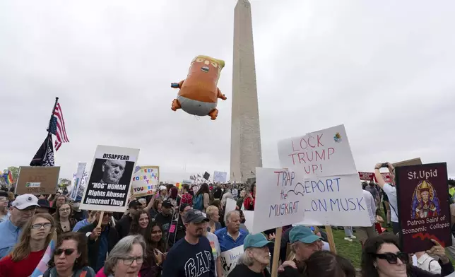 Demonstrators carry signs during the "Hands Off!" protests against President Donald Trump and Elon Musk at the Washington Monument in Washington, Saturday, April 5, 2025. (AP Photo/Jose Luis Magana)