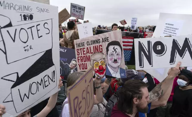 Demonstrators carry signs during the "Hands Off!" protests against President Donald Trump and Elon Musk at the Washington Monument in Washington, Saturday, April 5, 2025. (AP Photo/Jose Luis Magana)