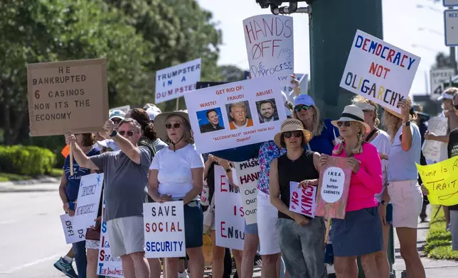 Activists protest President Donald Trump, who was a few miles away at his Trump National Golf Club, during a "Hands Off!" demonstration Saturday, April 5, 2025, in Palm Beach Gardens, Fla. (AP Photo/Alex Brandon)
