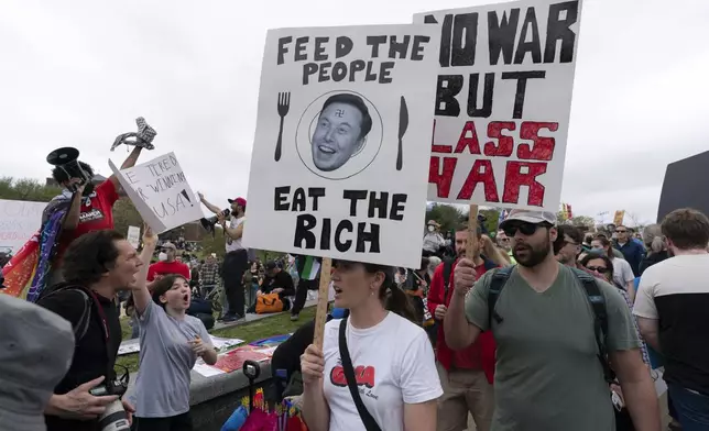 Demonstrators carry signs during the "Hands Off!" protests against President Donald Trump and Elon Musk at the Washington Monument in Washington, Saturday, April 5, 2025. (AP Photo/Jose Luis Magana)