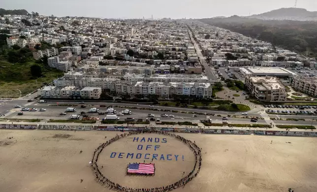 Protesters form a human banner on Ocean Beach during a protest against President Donald Trump, part of the "Hands Off" rallies held nationwide, in San Francisco, Saturday, April 5, 2025. (Stephen Lam/San Francisco Chronicle via AP)