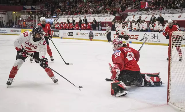Canada's Marie-Philip Poulin, left, scores past Swiss goalkeeper Andrea Braendli during the IIHF Women's World Championship, Group A, match between Switzerland and Canada, in Ceske Budejovice, Czech Republic, Friday, April 11, 2025. (Petr Skrivanek/CTK via AP)