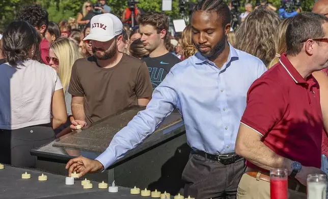 The day after an active shooter on campus Florida State students place electronic candles on a platform during a vigil on campus at Langford Green, Tallahassee, Fla., Friday, April 18, 2025. (AP Photo/Gary McCullough)