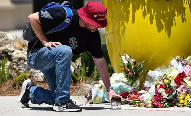 A student places a candle near the Florida State Student Union building, Tallahassee, Fla., Friday, April 18, 2025. (AP Photo/Gary McCullough)