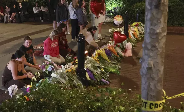 An impromptu memorial shared online brings students bearing flowers into the evening near the center of the Florida State campus in sight of the Student Union building, Tallahassee, Fla., Thursday, April 17, 2025. (AP Photo/Gary McCullough)