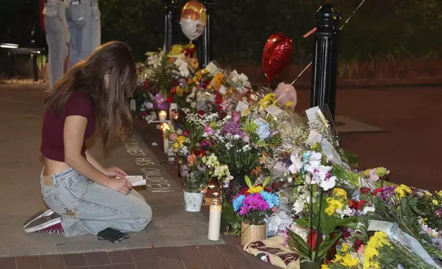 An impromptu memorial shared online brings students bearing flowers into the evening near the center of the Florida State campus in sight of the Student Union building, Tallahassee, Fla., Thursday, April 17, 2025. (AP Photo/Gary McCullough)