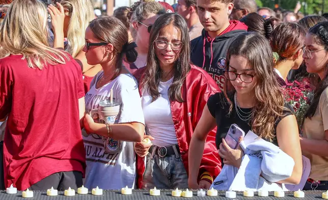 The day after an active shooter on campus Florida State students place electronic candles on a platform during a vigil on campus at Langford Green, Tallahassee, Fla., Friday, April 18, 2025. (AP Photo/Gary McCullough)