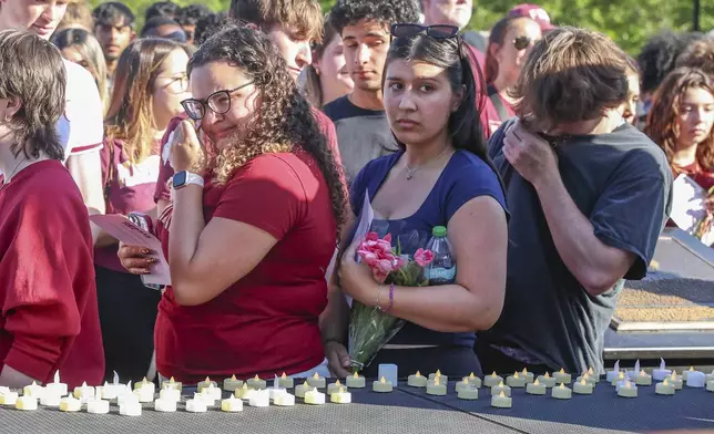 The day after an active shooter on campus Florida State students place electronic candles on a platform during a vigil on campus at Langford Green, Tallahassee, Fla., Friday, April 18, 2025. (AP Photo/Gary McCullough)
