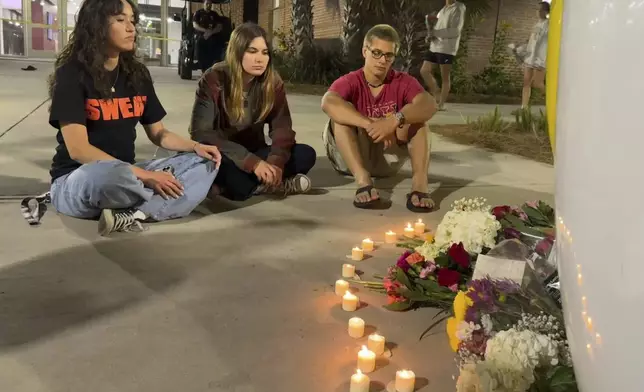 People sit in front of a makeshift memorial outside the student union at Florida State University, Thursday, April 17, 2025, in Tallahassee, Fla., following a campus shooting. (AP Photo/Kate Payne)