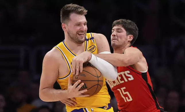 Houston Rockets guard Reed Sheppard, right, reaches in on Los Angeles Lakers guard Luka Doncic during the first half of an NBA basketball game Friday, April 11, 2025, in Los Angeles. (AP Photo/Mark J. Terrill)