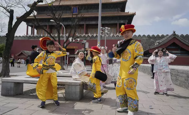 Tourists dressed as emperors react to strong winds outside the Forbidden City in Beijing, China, Saturday, April 12, 2025. (AP Photo/Ng Han Guan)