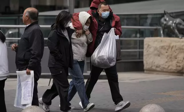 Residents walk against strong winds in Beijing, China, Saturday, April 12, 2025. (AP Photo/Ng Han Guan)