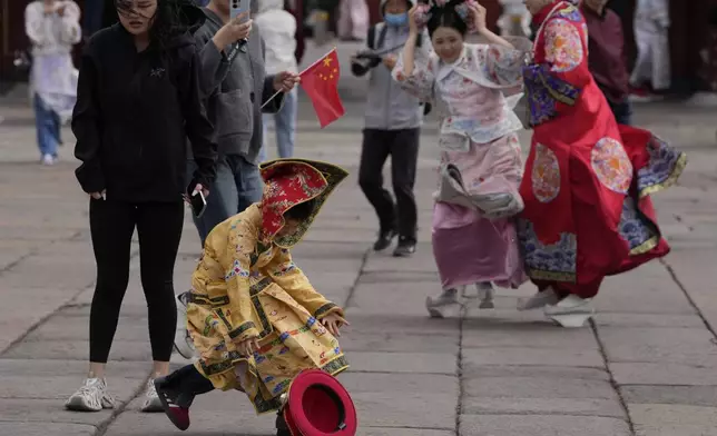 A child dressed as the emperor runs after his crown blown away outside the Forbidden City during high winds in Beijing, China, Saturday, April 12, 2025. (AP Photo/Ng Han Guan)