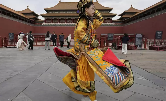 A woman dressed as the dowager reacts to strong winds outside the Forbidden City which was closed due to gale wind alerts in Beijing, China, Saturday, April 12, 2025. (AP Photo/Ng Han Guan)