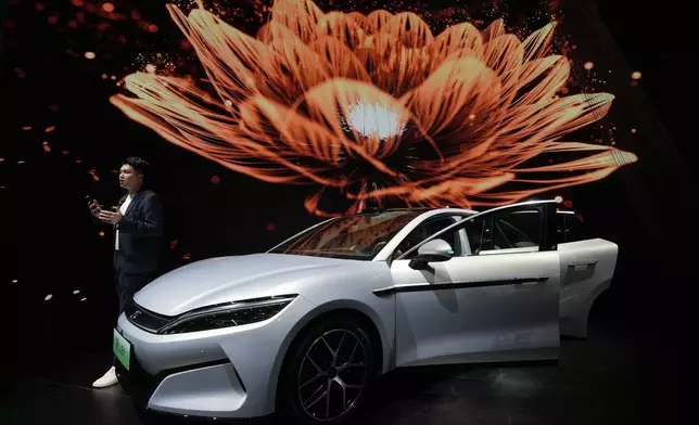 A man talks near the Han L EV model from BYD during the Shanghai auto show on Wednesday, April 23, 2025. (AP Photo/Ng Han Guan)