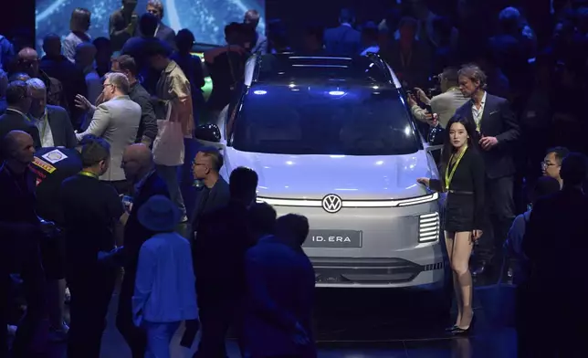 Attendees look at the latest cars from Volkswagen Group during the media night ahead of the Auto Show in Shanghai, Tuesday, April 22, 2025. (AP Photo/Ng Han Guan)