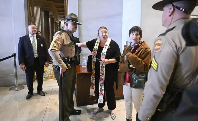 State troopers stop Ingrid McIntyre and Michele Flynn, second from right, as McIntyre argues to go inside the Senate after protesting an immigration bill outside the chamber at the state Capitol Thursday, April 10, 2025 in Nashville, Tenn. (AP Photo/John Amis)