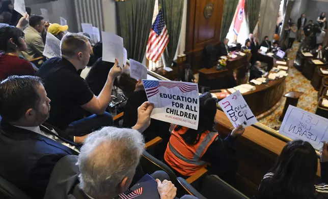 Demonstrators hold up signs protesting an immigration bill as it is discussed in the Senate chamber at the state Capitol Thursday, April 10, 2025 in Nashville, Tenn. (AP Photo/John Amis)
