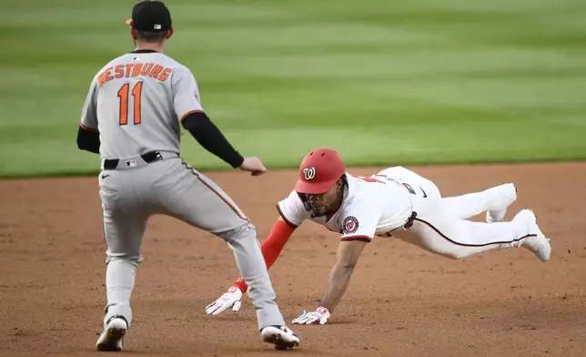 Washington Nationals' Jose Tena, right, slides towards third base for a triple against Baltimore Orioles third baseman Jordan Westburg (11) during the second inning of a baseball game, Tuesday, April 22, 2025, in Washington. (AP Photo/Nick Wass)