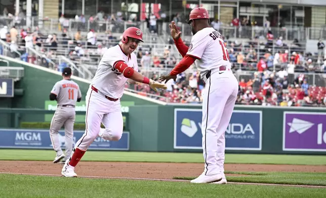 Washington Nationals' Nathaniel Lowe, left, celebrates his two-run home run with third base coach Ricky Gutierrez, right, during the first inning of a baseball game against the Baltimore Orioles, Tuesday, April 22, 2025, in Washington. (AP Photo/Nick Wass)