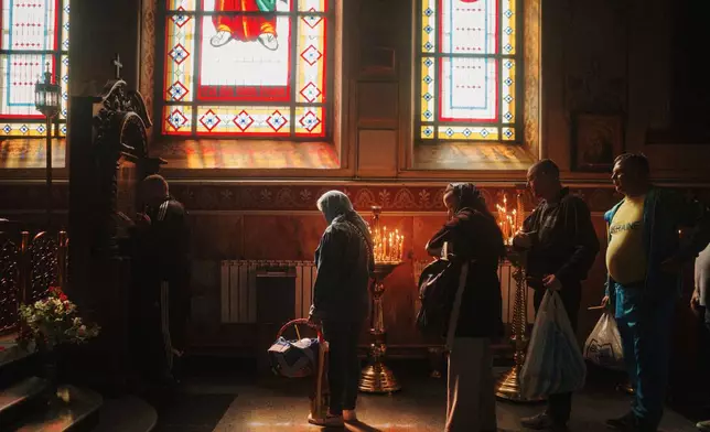 People stand in line to kiss an icon during the celebration of Orthodox Easter at Cross Lower Church of the Ukrainian Orthodox Church in Kharkiv, Ukraine, on Sunday, April 20, 2025. (AP Photo/George Ivanchenko)