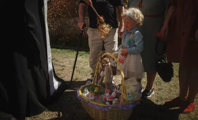 Father Henadii blesses a girl and Easter basket during the celebration of Orthodox Easter at St. John Theologian Church of the Orthodox Church of Ukraine in Kharkiv, Ukraine, on Sunday, April 20, 2025. (AP Photo/George Ivanchenko)