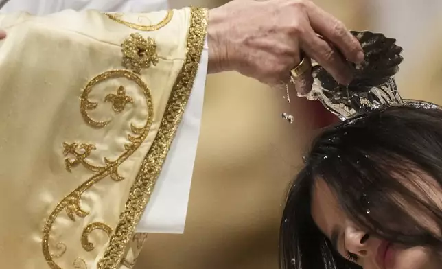Dean of the College of Cardinals Giovanni Battista Re baptizes a woman as he leads the Easter vigil inside St. Peter's Basilica at the Vatican, Saturday, April 19, 2025. (AP Photo/Alessandra Tarantino)