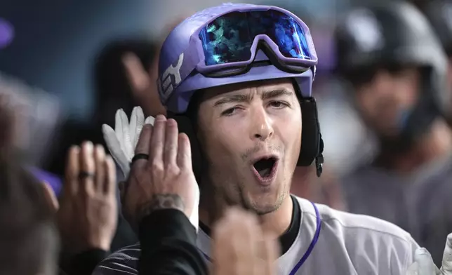 Colorado Rockies' Michael Toglia is congratulated by teammates in the dugout after hitting a grand slam during the Xhird inning of a baseball game against the Los Angeles Dodgers, Wednesday, April 16, 2025, in Los Angeles. (AP Photo/Mark J. Terrill)
