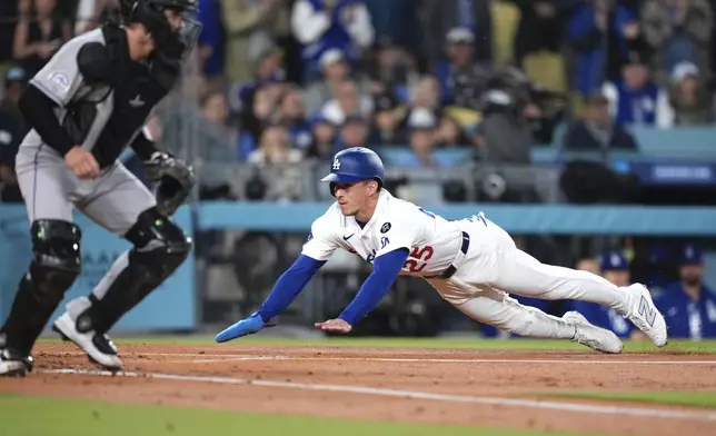 Los Angeles Dodgers' Tommy Edman, right, scores on a single by Andy Pages as Colorado Rockies catcher Braxton Fulford waits for the ball during the first inning of a baseball game Wednesday, April 16, 2025, in Los Angeles. (AP Photo/Mark J. Terrill)