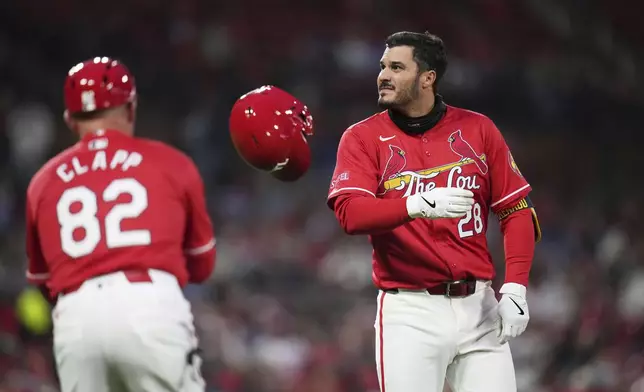 St. Louis Cardinals' Nolan Arenado (28) tosses his helmet to first base coach Stubby Clapp (82) after flying out to end the first inning of a baseball game against the Philadelphia Phillies Friday, April 11, 2025, in St. Louis. (AP Photo/Jeff Roberson)