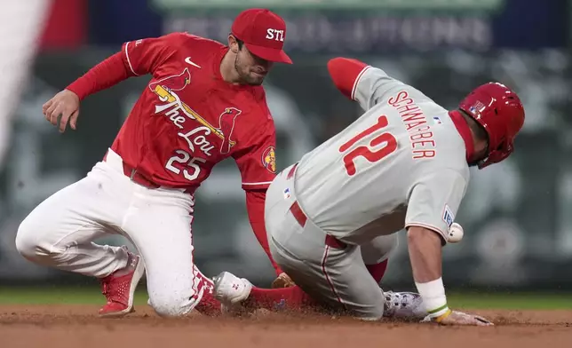 Philadelphia Phillies' Kyle Schwarber (12) is safe at second for a stolen base as the throw gets past St. Louis Cardinals second baseman Thomas Saggese during the first inning of a baseball game Friday, April 11, 2025, in St. Louis. (AP Photo/Jeff Roberson)