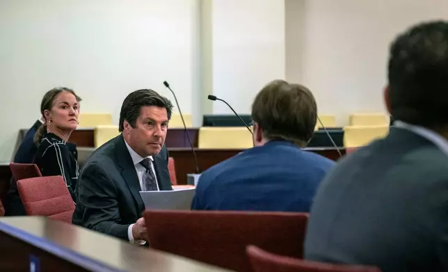 Kurt Sommer, representing the personal representative of the Hackman estate, Julia Peters, hands documents over to Walker Boyd, attorney for Santa Fe County in court before Judge Matthew J. Wilson in District Court in Santa Fe, N.M., Monday, March 31, 2025. (Michael G. Seamans/Santa Fe New Mexican via AP)