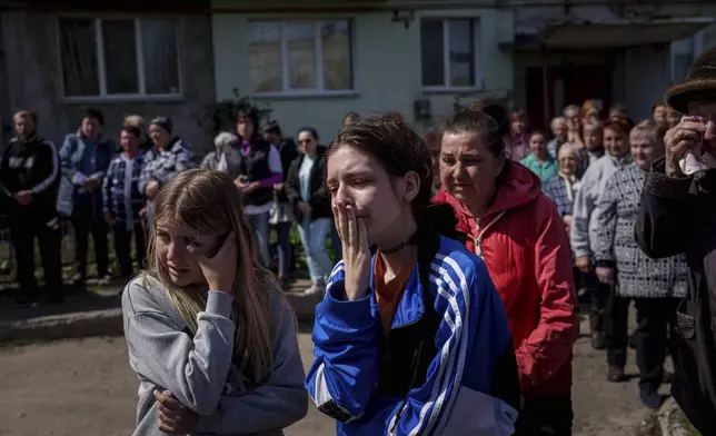 Children cry during a farewell ceremony for Maksym Martynenko, 11, Natalia Martynenko, 49, and Mykola Martynenko, 41, killed in a deadly Palm Sunday Russian attack on Sumy on April 13, in Stare Selo village near Sumy, Ukraine, Wednesday, April 16, 2025. (AP Photo/Evgeniy Maloletka)